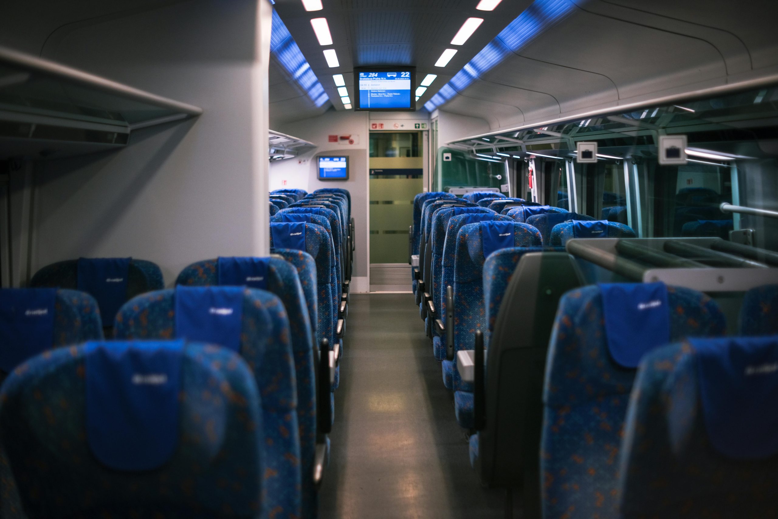 A serene scene of a modern train's interior with empty blue seats, ready for passengers.